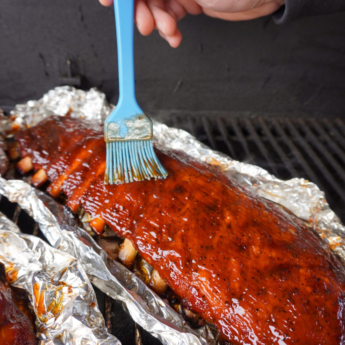 Brushing bbq sauce on the ribs.