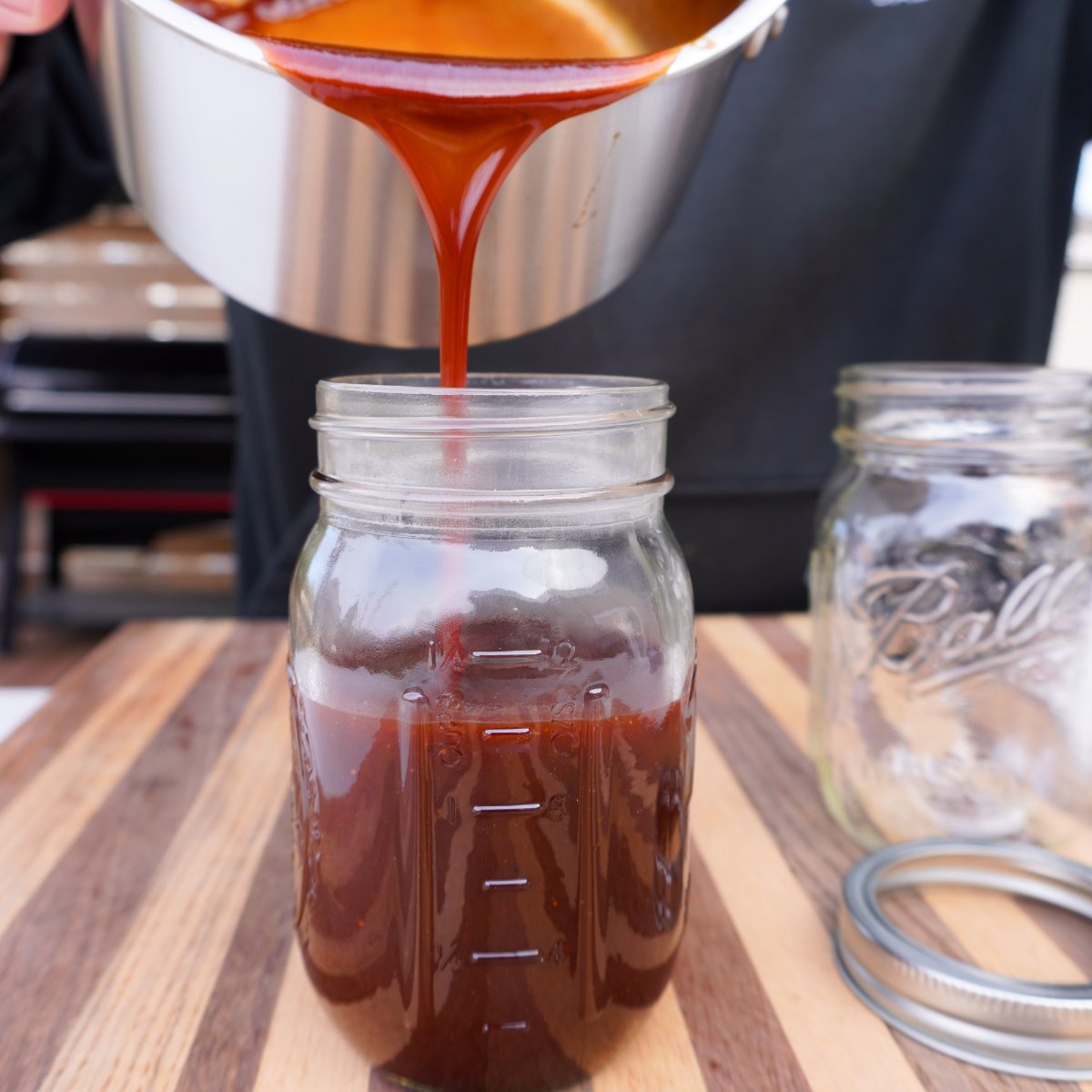 Pouring bbq sauce into a mason jar.
