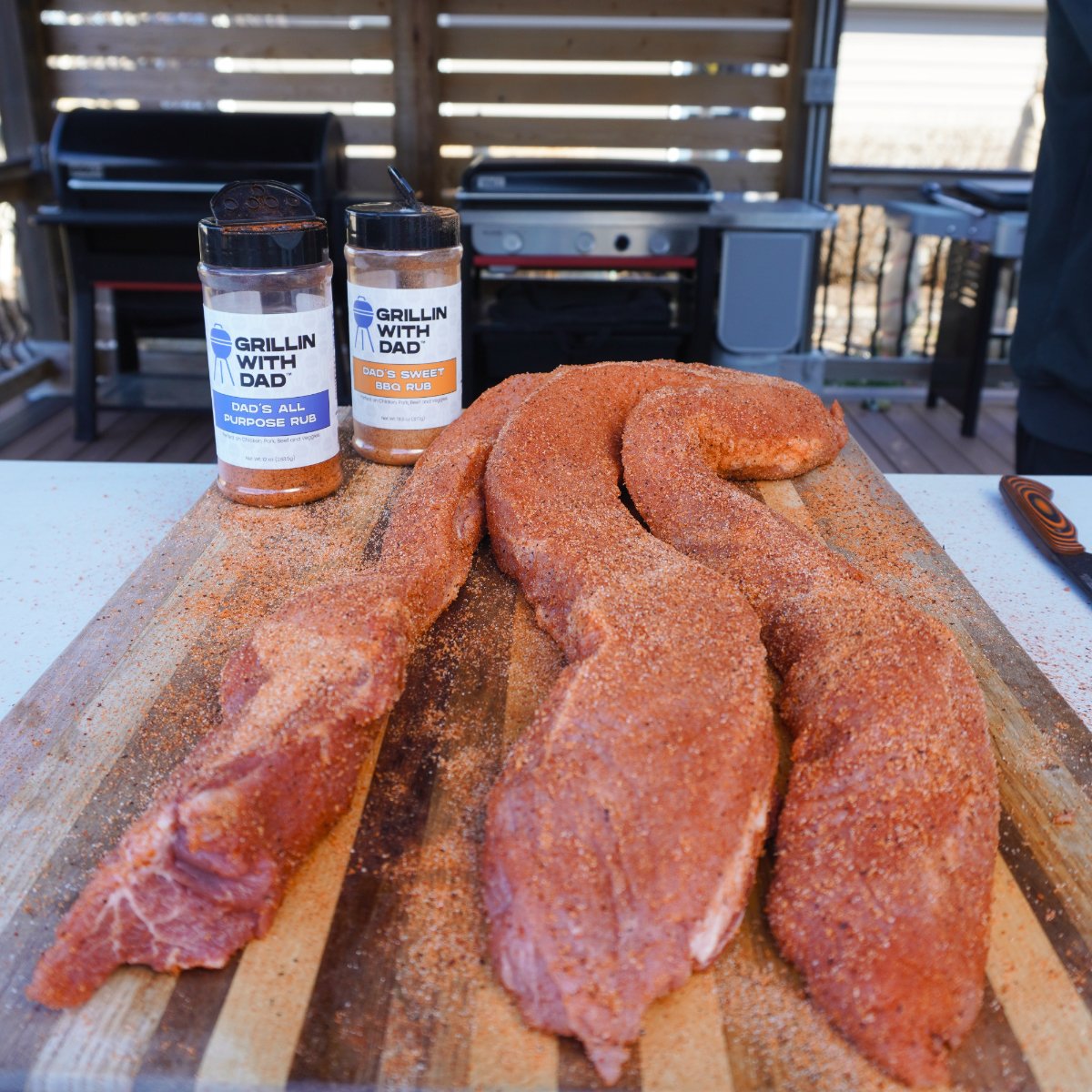 seasoned pork loin strips on a cutting board with the seasoning bottles in the far left corner.