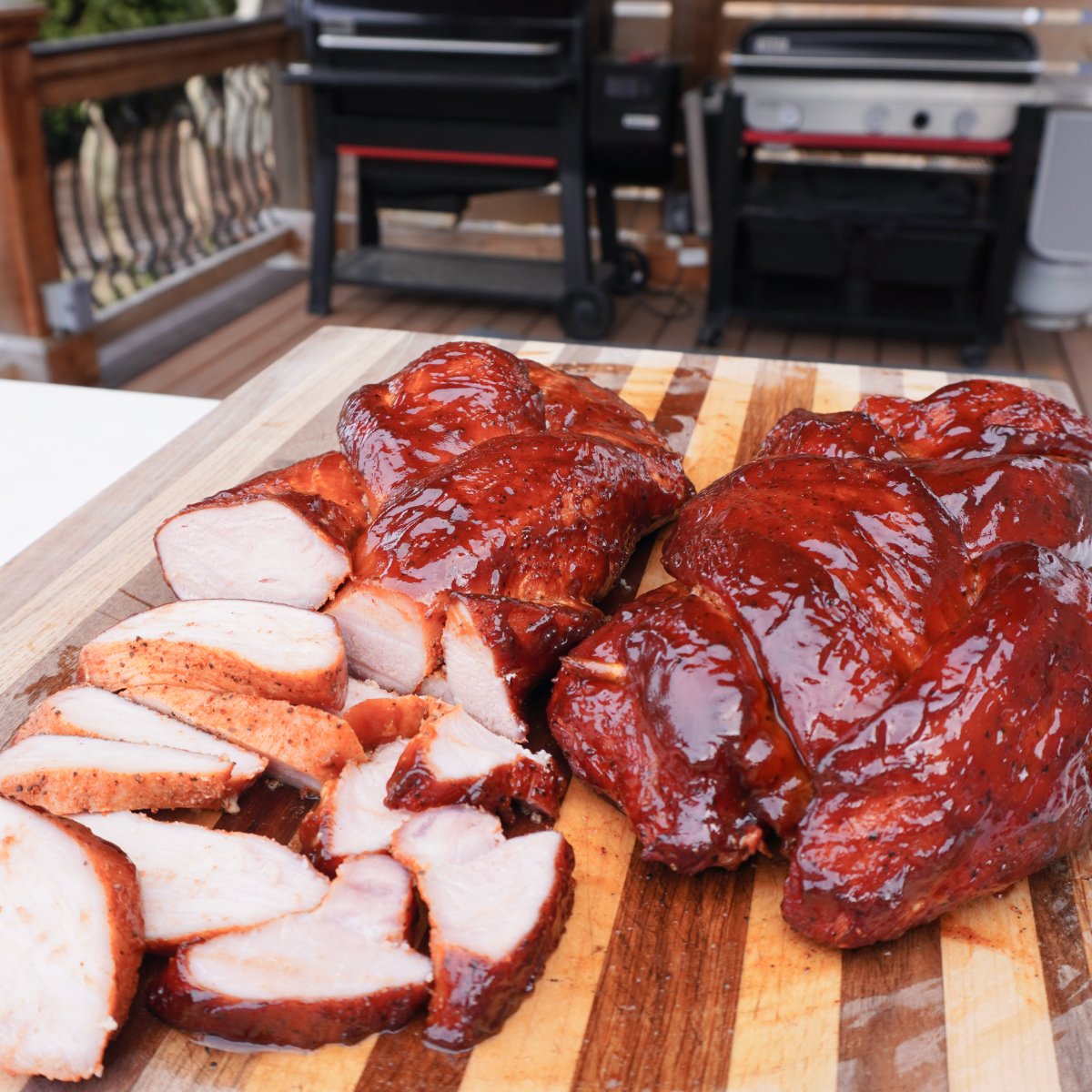 Sliced braided pork loin with bbq sauce on cutting board.