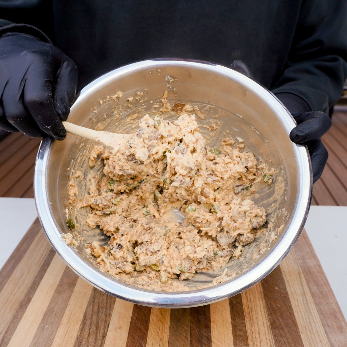 cheesesteak mixture in a large metal bowl scooped with a wooden spoon.