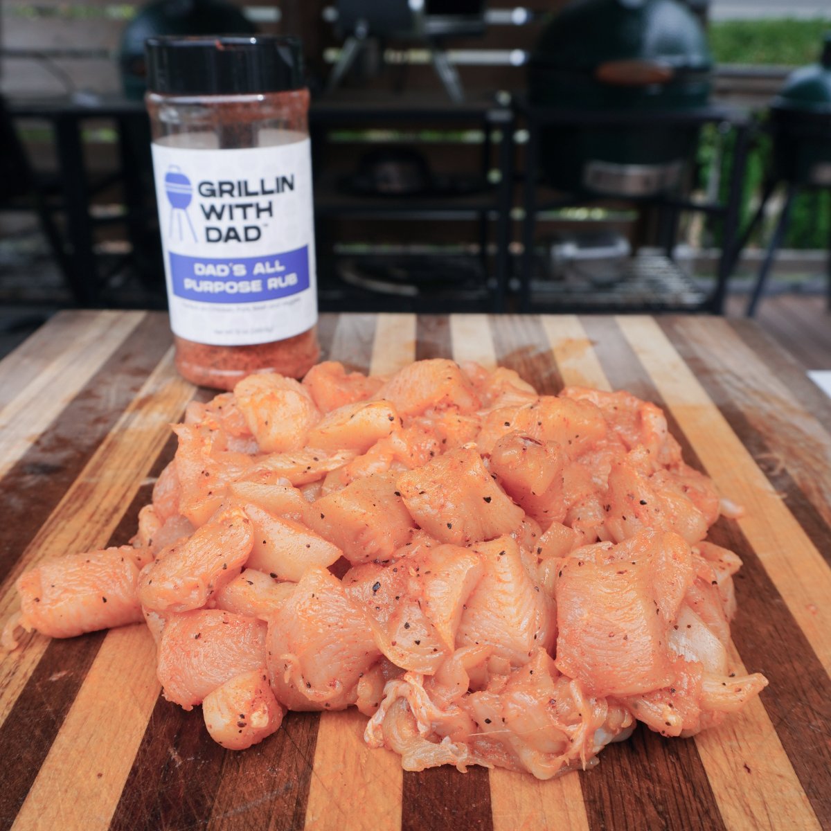 Raw cubed up and seasoned chicken with a bottle of the seasoning behind it.