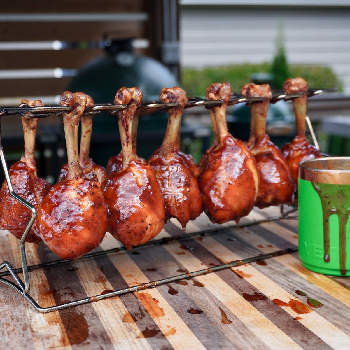 cooked chicken lollipops hanging on a rack on a cutting board. 
