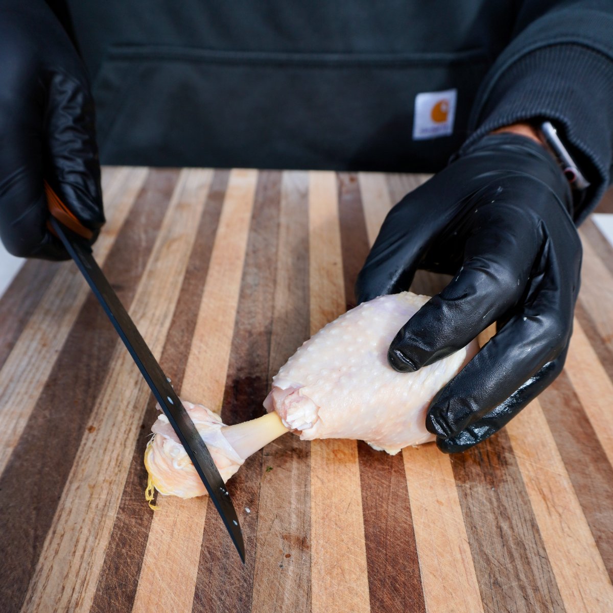 knife scraping the bone of a chicken drumstick.