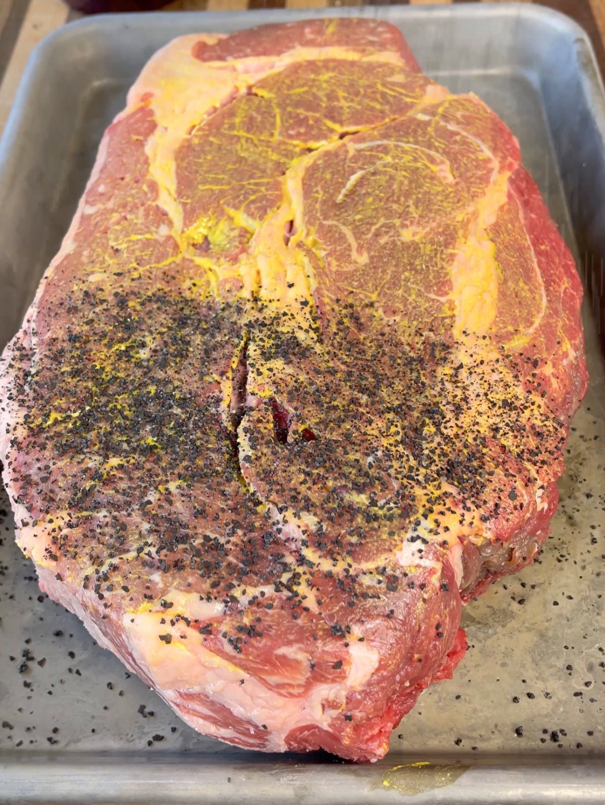 beef chuck roast with mustard and seasoning on top. 