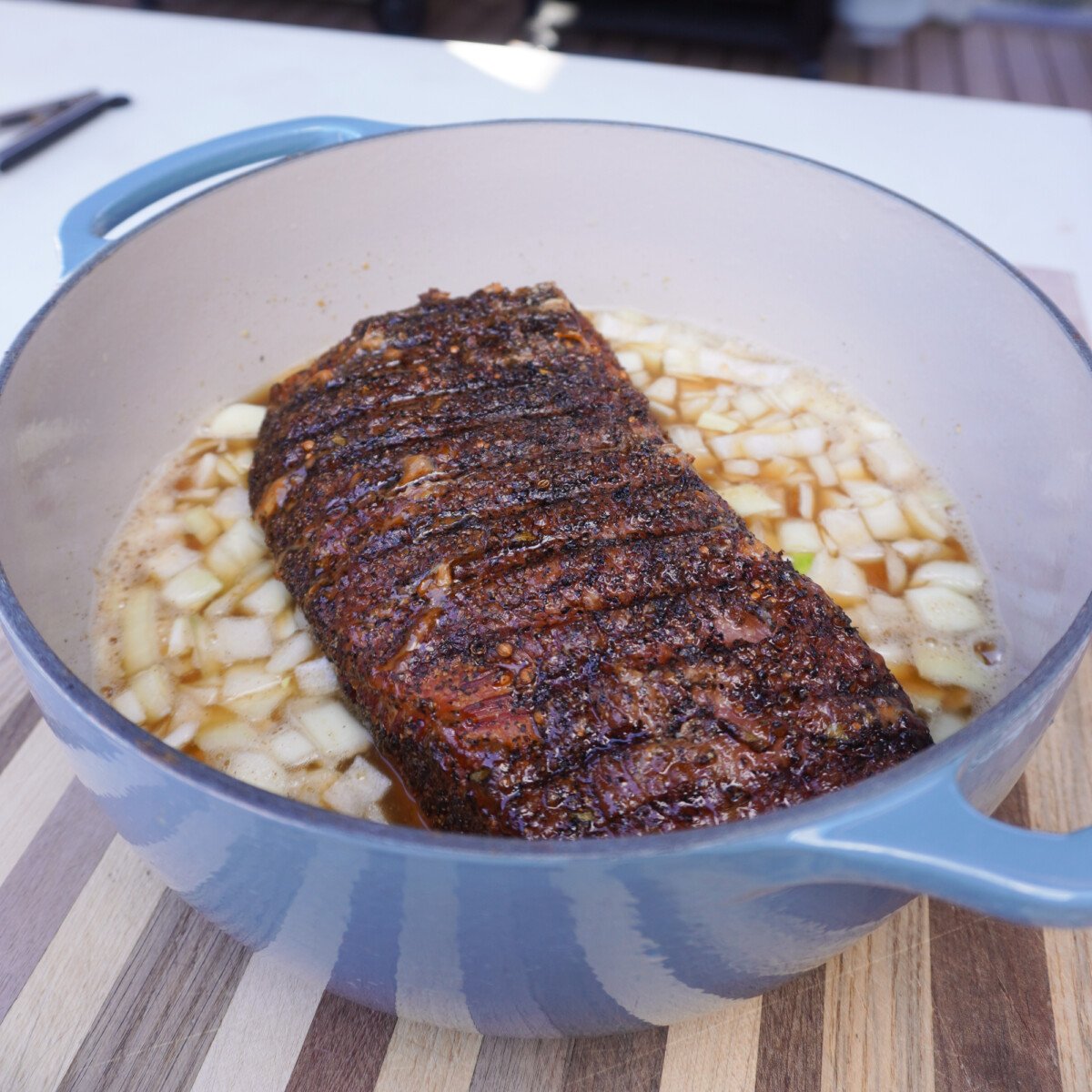 braised corned beef in dutch oven on a bed on chopped onions.