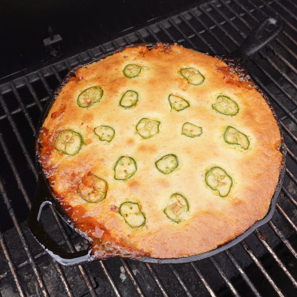 smoked cornbread cowboy casserole in a cast iron skillet on the grill