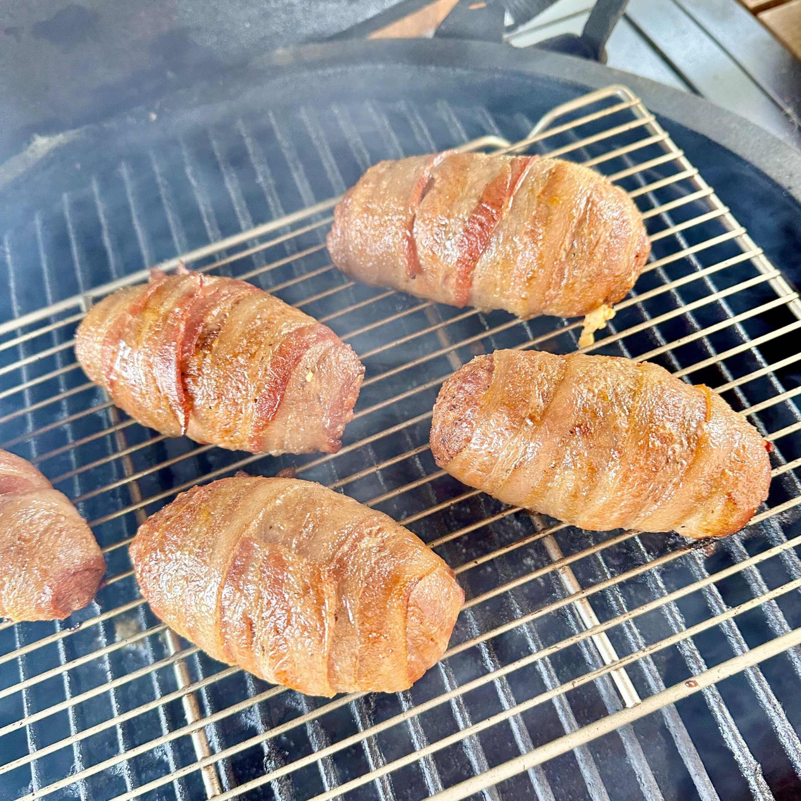 bacon wrapped Armadillo eggs smoking on the grill.