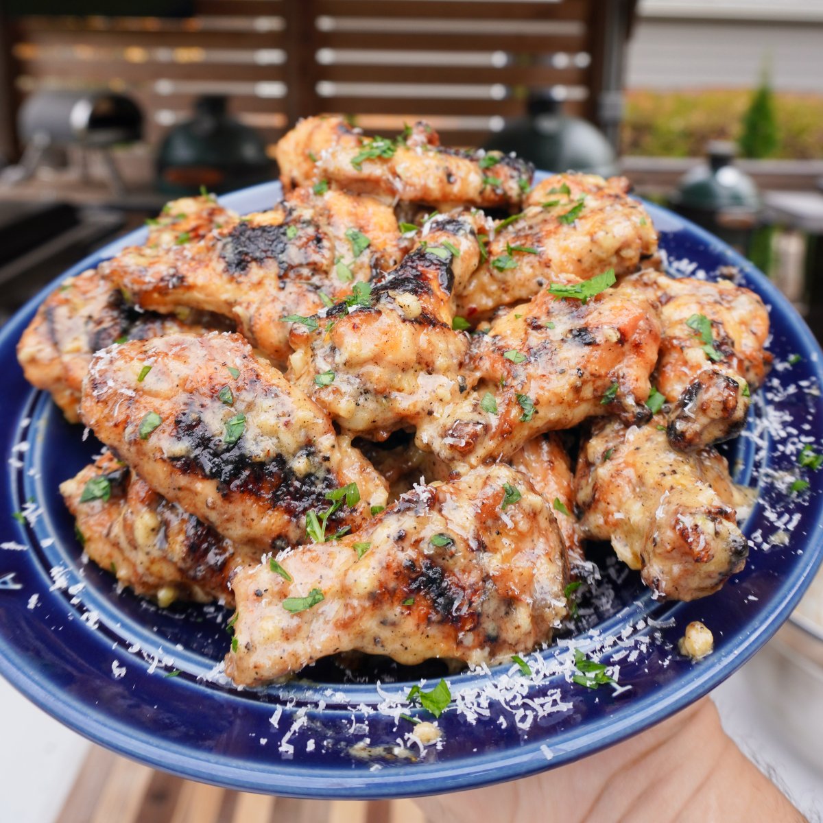cooked garlic parmesan wings on a blue plate. 