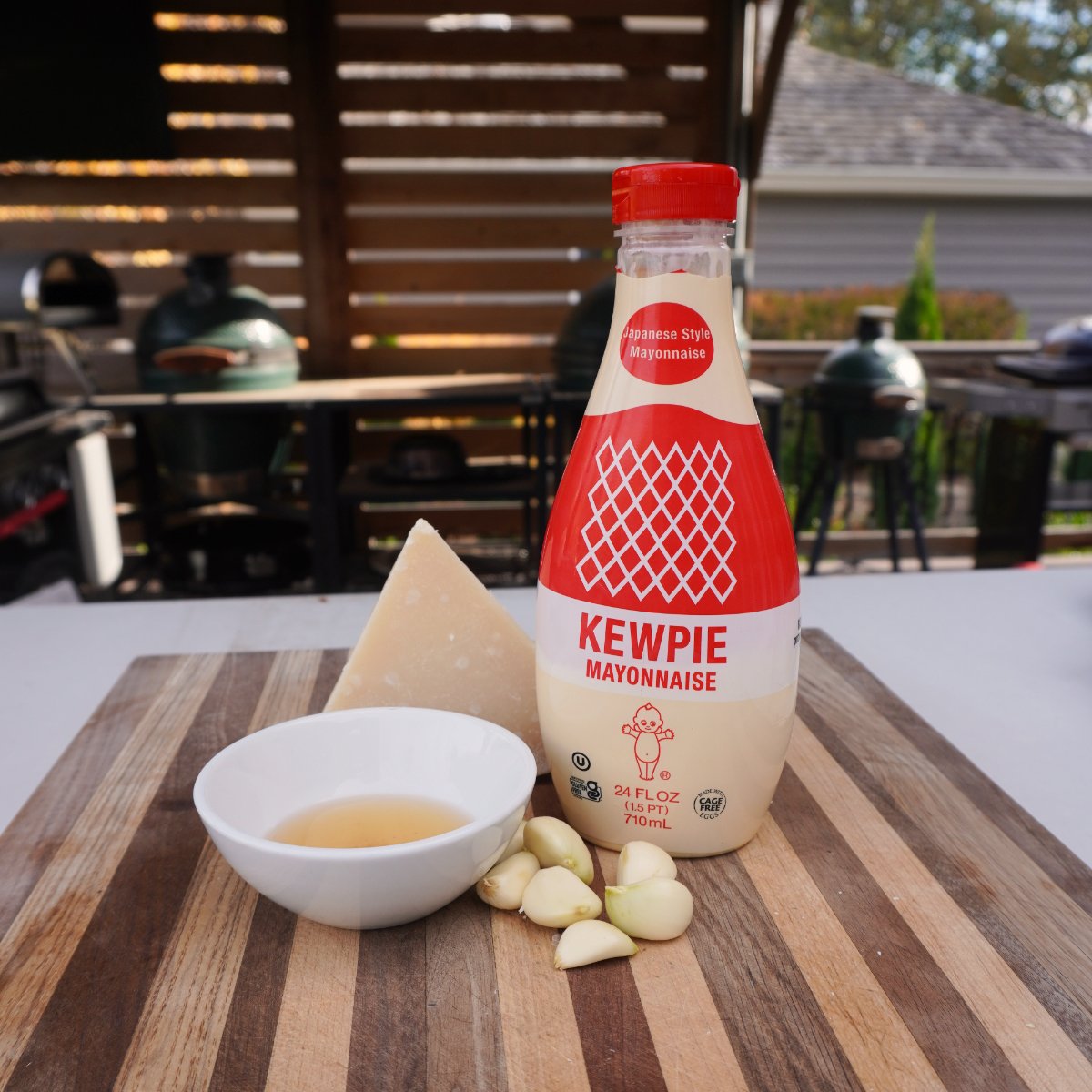 bottle of mayo, garlic, parmesan cheese and apple cider vinegar on a cutting board. 