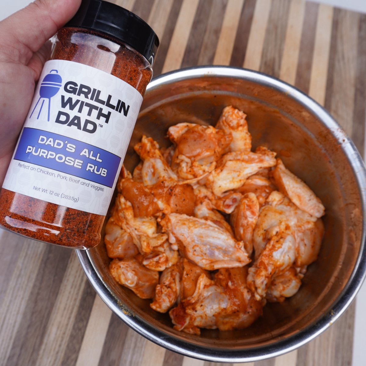 raw chicken wings seasoned with dads all purpose rub in a bowl. 