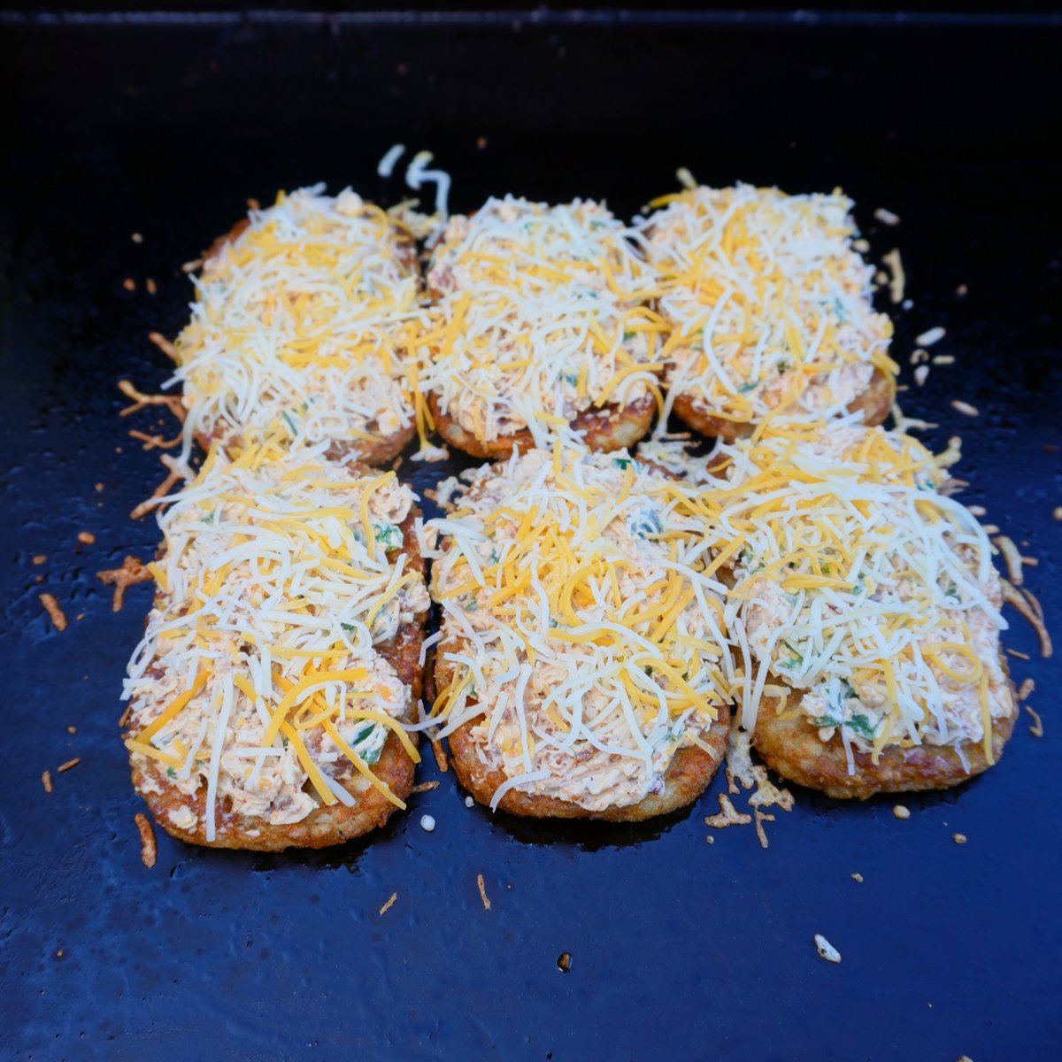 Six hash browns topped with a jalapeno popper dip and shredded cheese.
