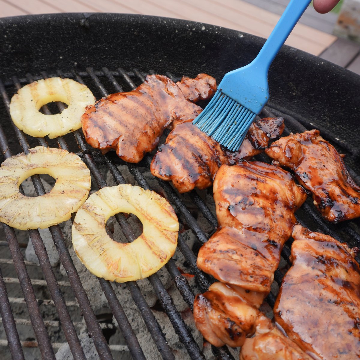 chicken on the grill getting brushed with sauce. 