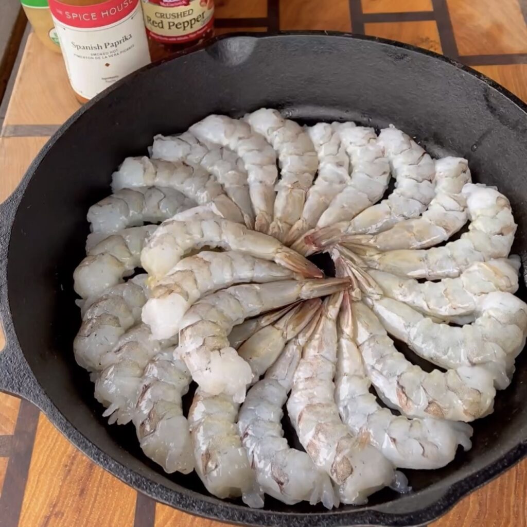 Raw shrimp lined in a cast iron skillet. 