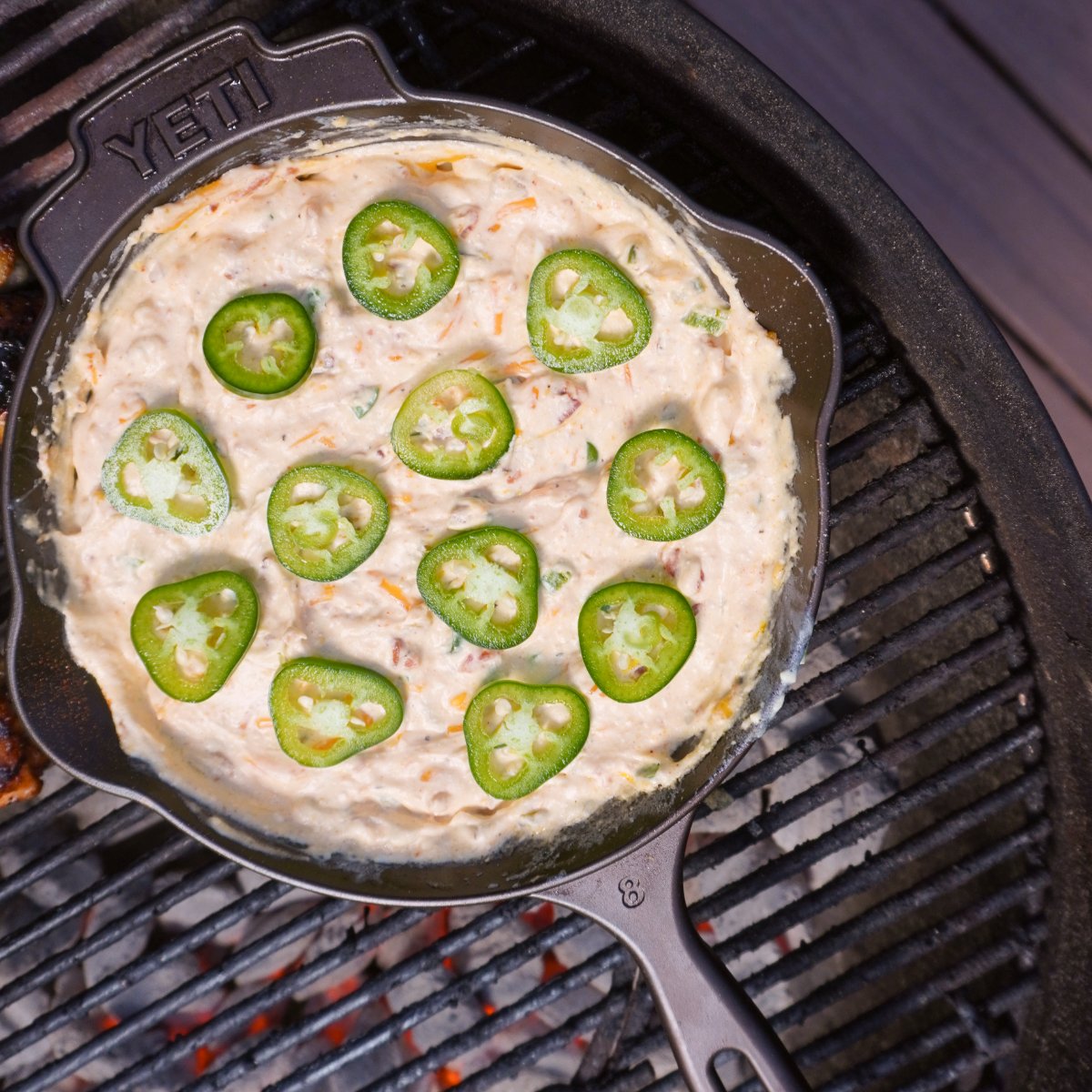 Raw jalapeno popper dip in a cast iron skillet on the grill
