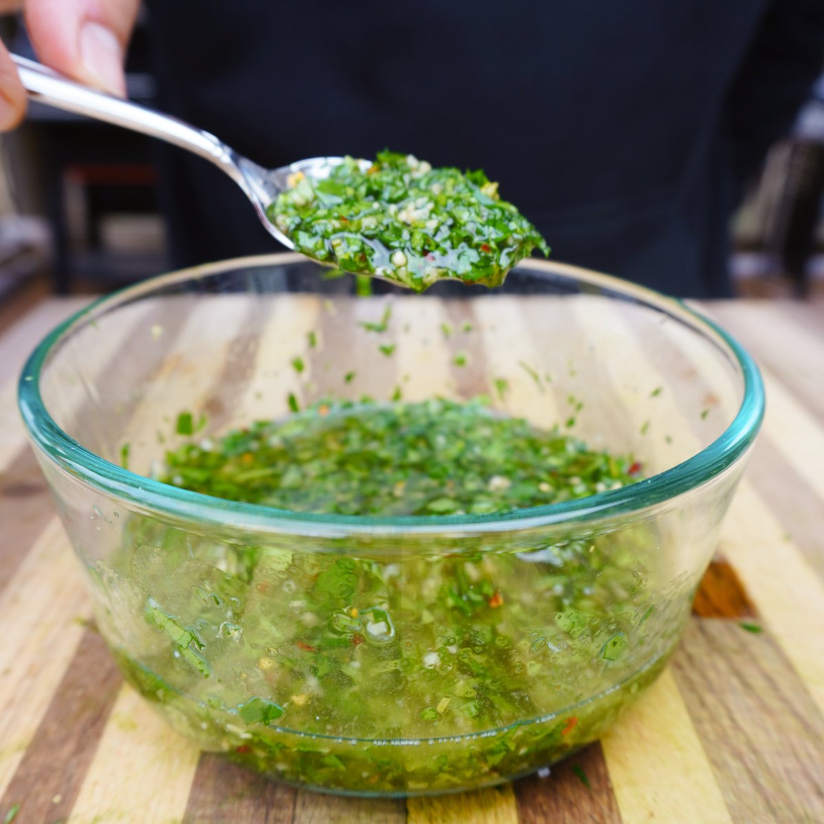mint chimichurri sauce in a glass bowl scooped up with a small spoon.