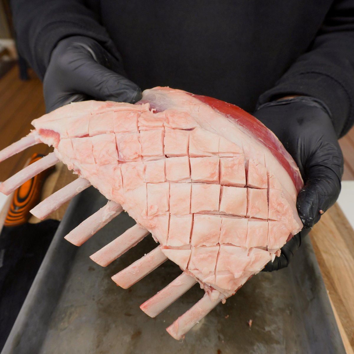 scored trimmed raw rack of lamb showed off by hands