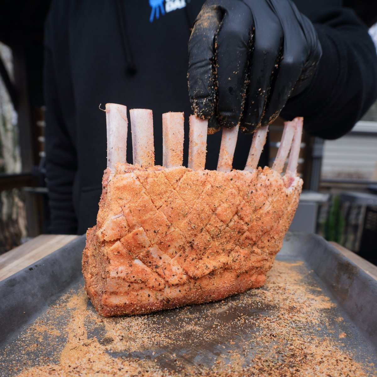seasoned raw rack of lamb up right on a metal tray.