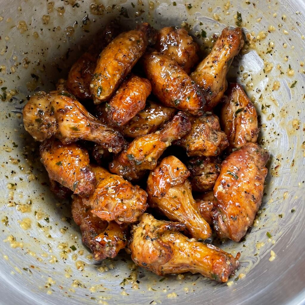 lemon garlic wings tossed in sauce in a bowl. 