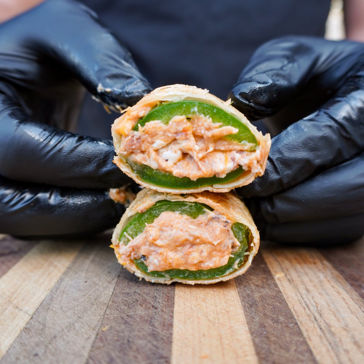 sliced in half jalapeno popper lumpia showing the crunchy wrapper shell, jalapeno skin and creamy filling.