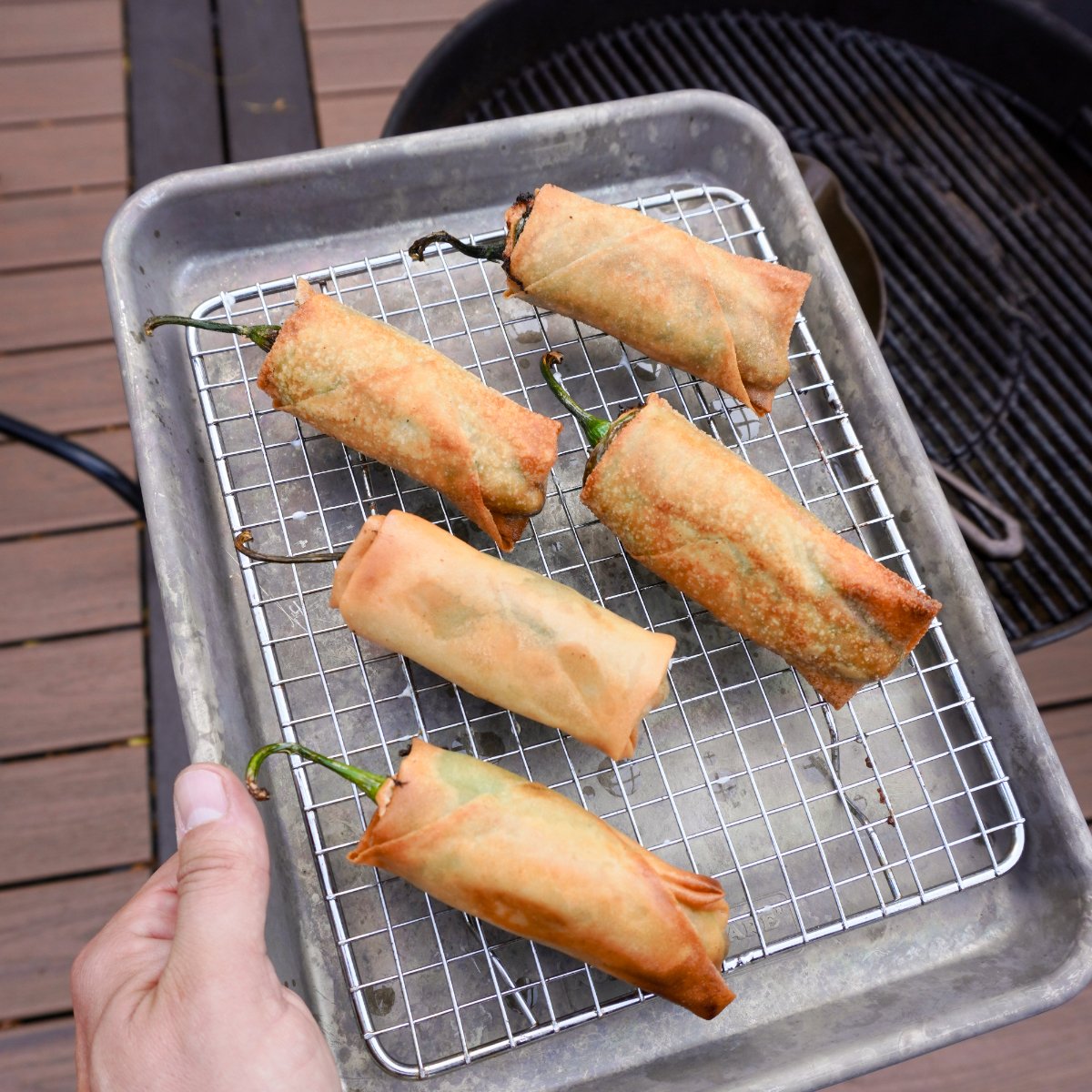 deep fried jalapeno popper lumpia's drying on a wire rack.