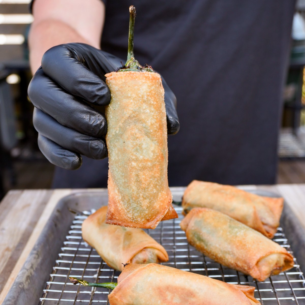 deep fried jalapeno popper lumpia held vertically over a tray.