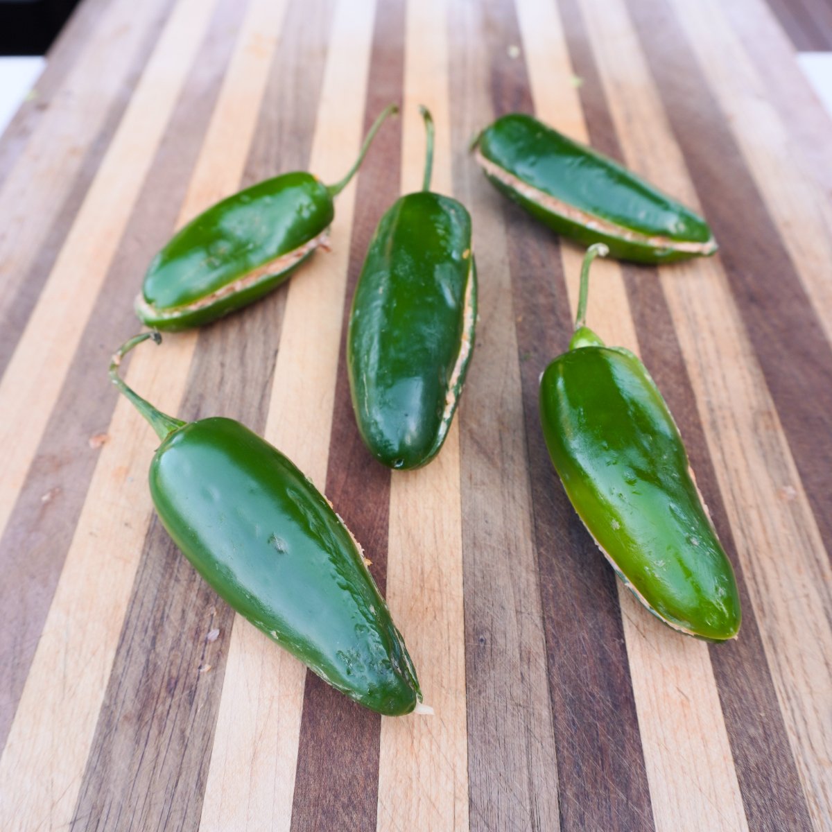 filled and closed jalapeno poppers on a cutting board.