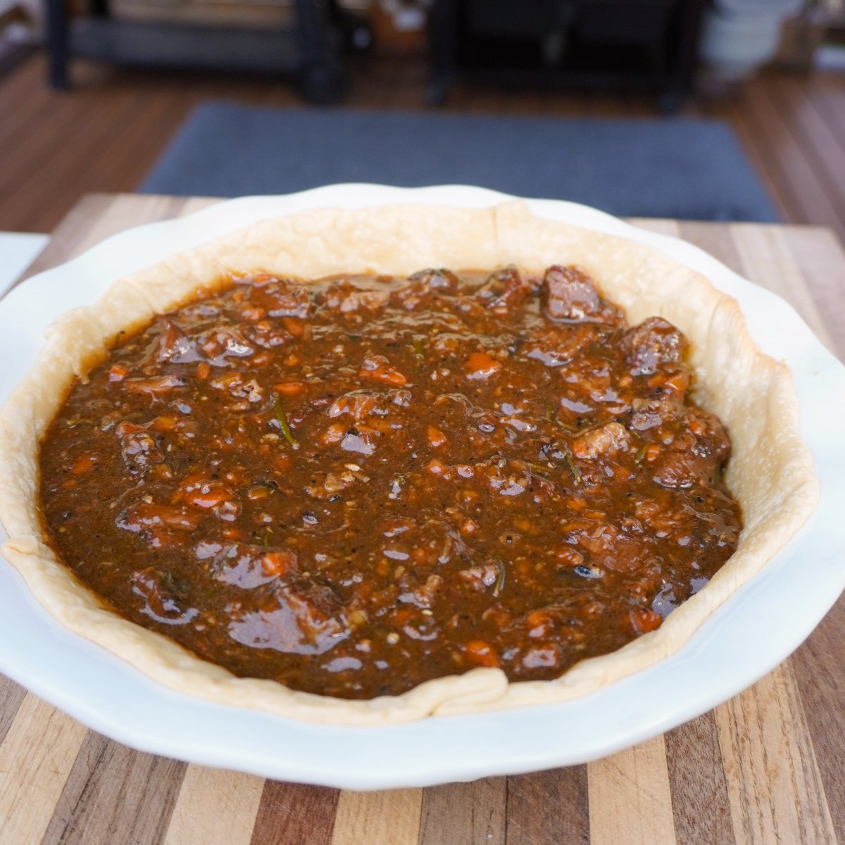 meat gravy filled bottom baked pie crust in a white pie bowl.