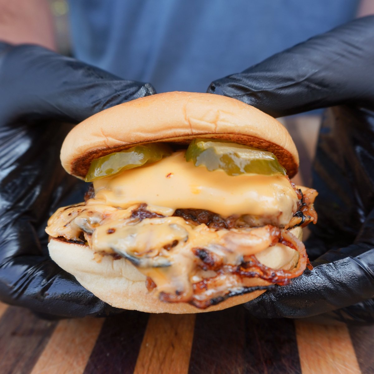 An assembled Oklahoma Onion Burger held by 2 hands.
