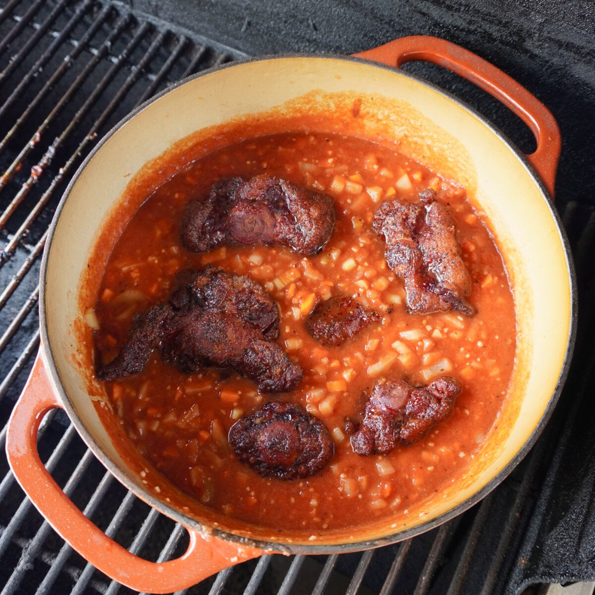 braising oxtail in a dutch oven on a smoker.