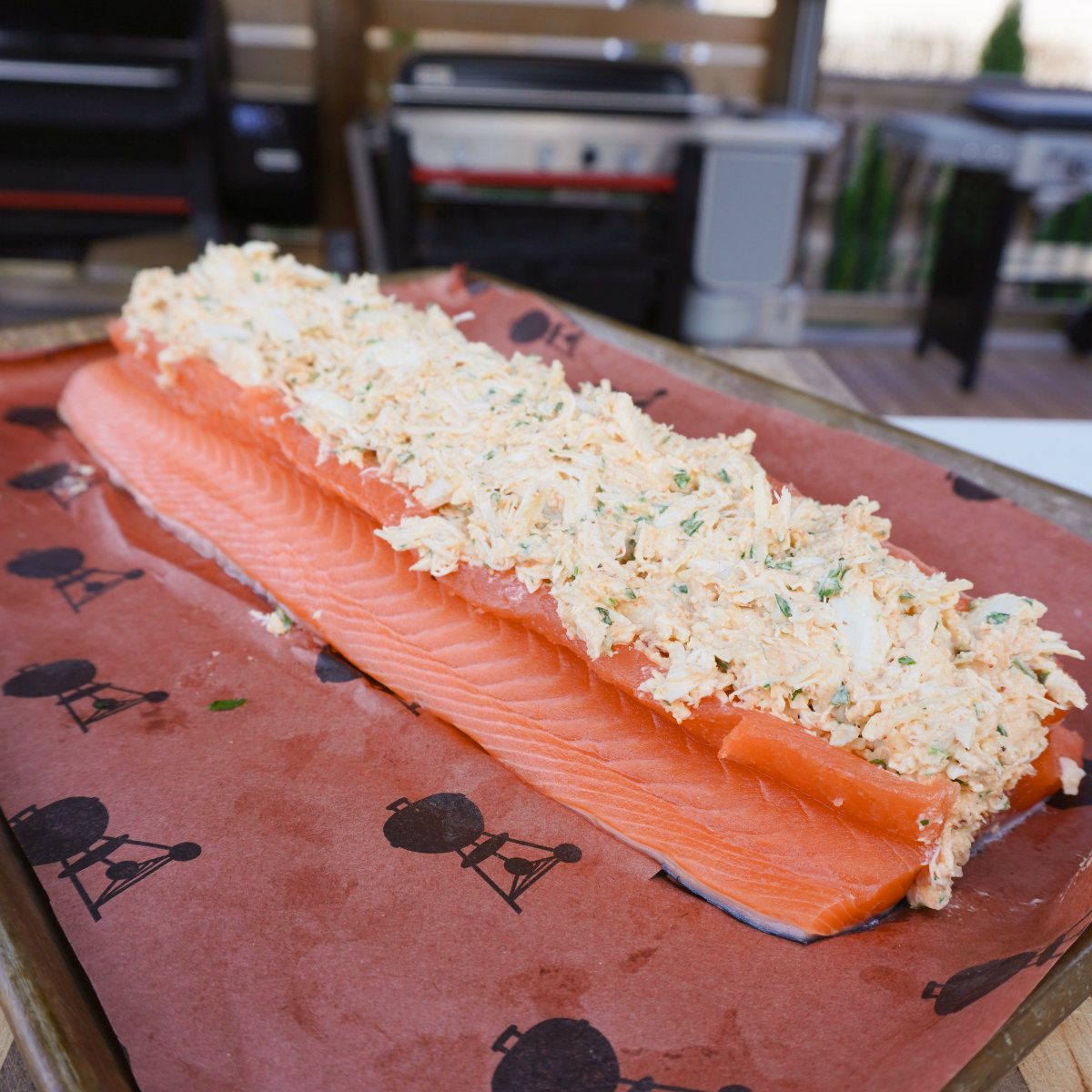 raw crab stuffed salmon filet on butcher paper ready to go on the grill.