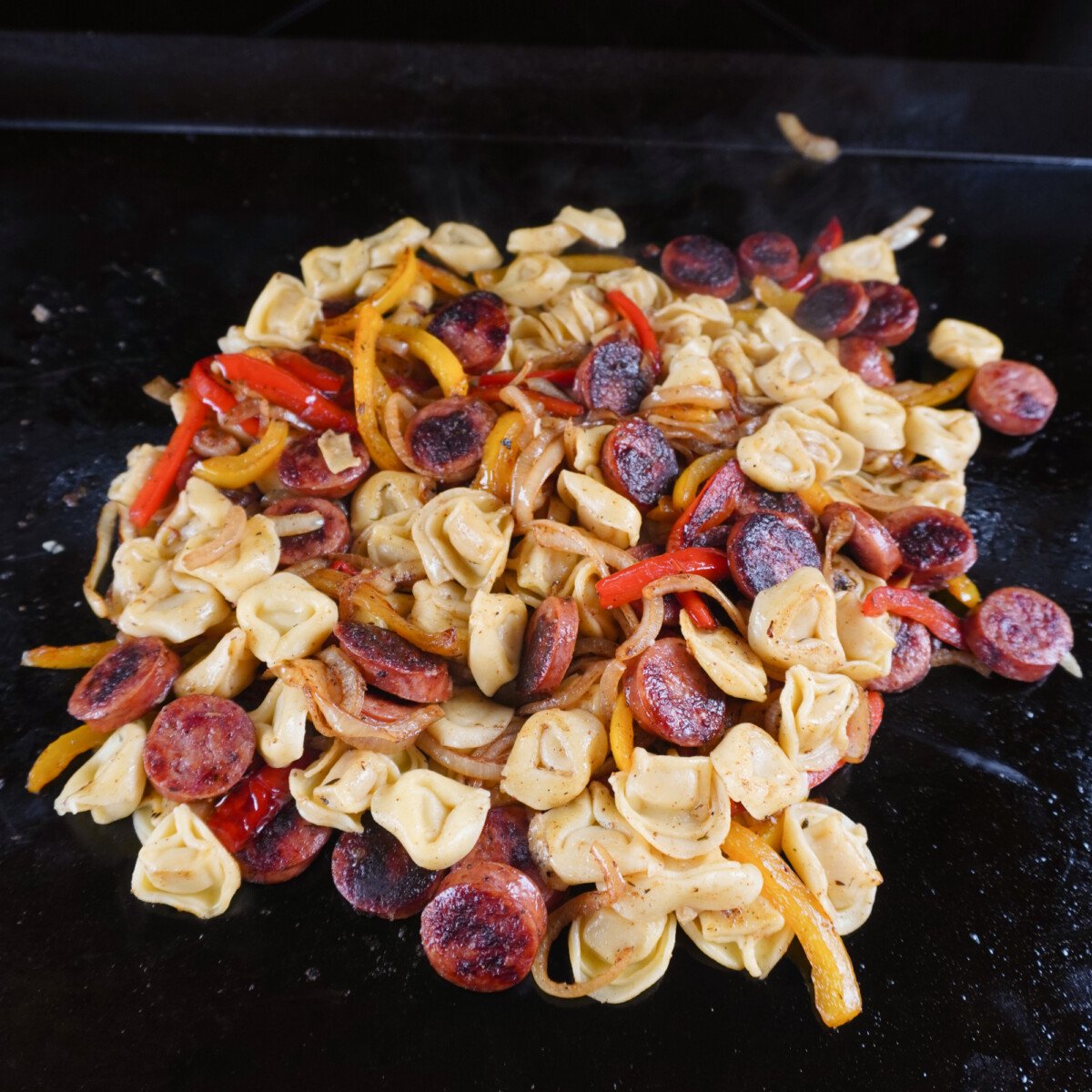 mixed grilled sausage and tortellini on griddle.
