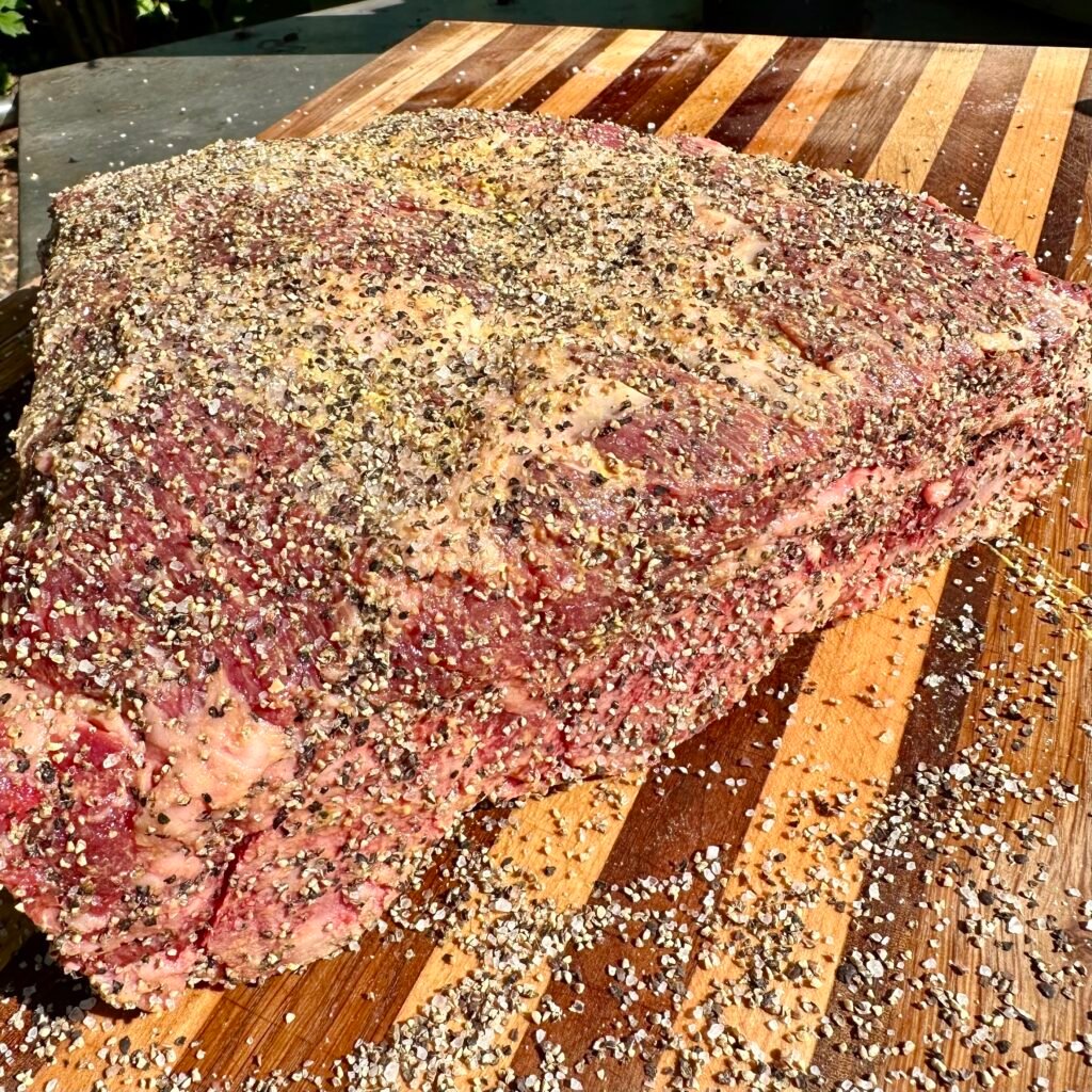 Seasoned rack of raw beef ribs on a cutting board. 