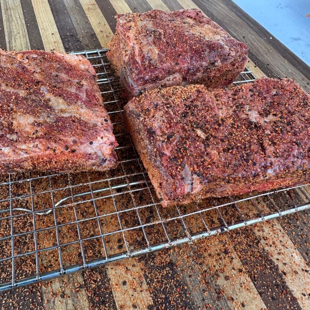 seasoned beef short ribs on a wire rack.