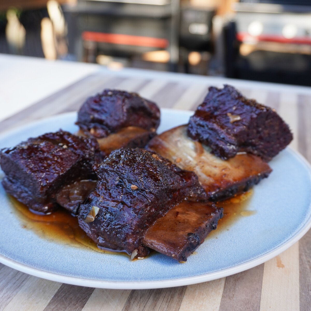cooked short ribs on a plate with sauce. 