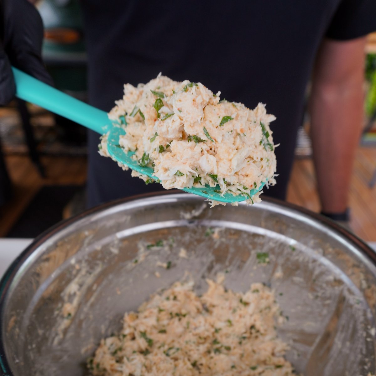 crab meat stuffing on in a bowl and silicone spoon.