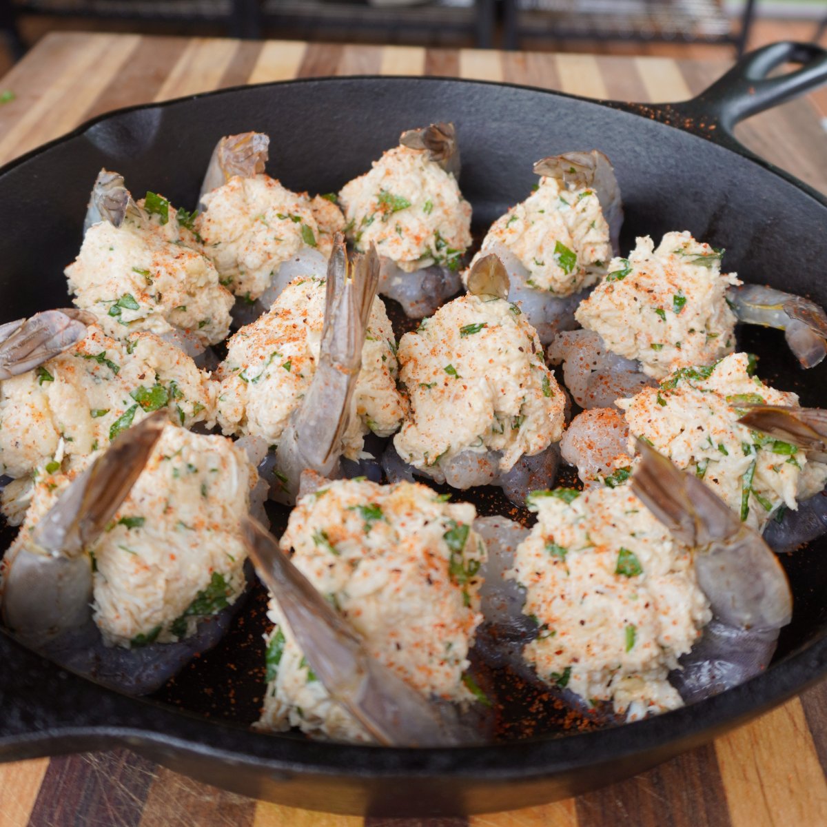 raw shrimp stuffed with crab meat studding in a cast iron skillet.