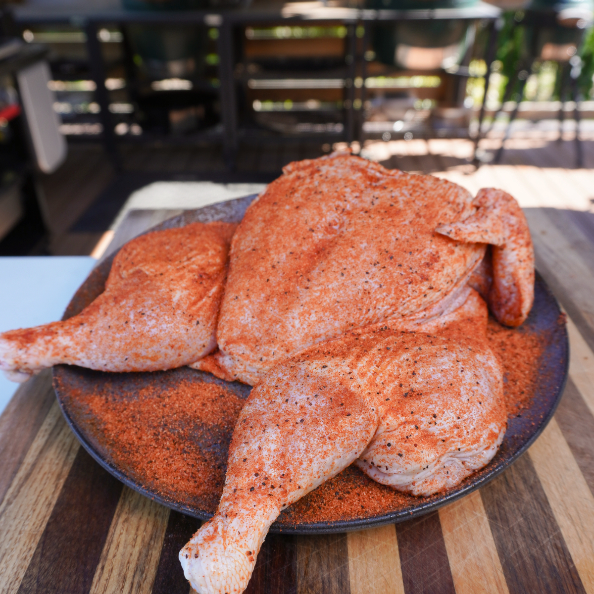 seasoned spatchcocked chicken seasoned on a round grey plate.
