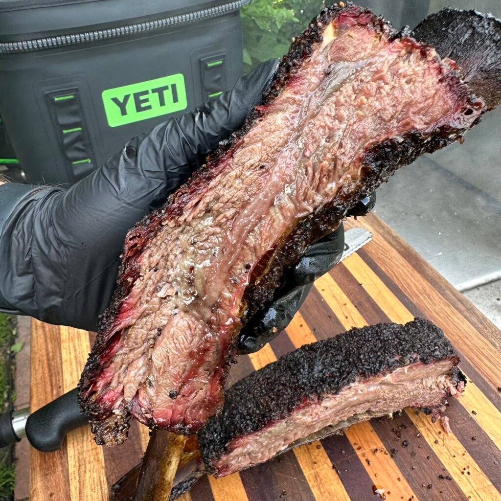 Smoked beef ribs held in hand.