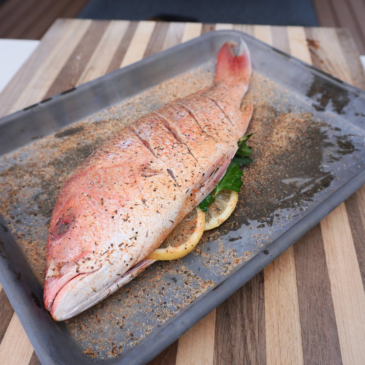 stuffed and seasoned raw red snapper on a metal sheet pan.