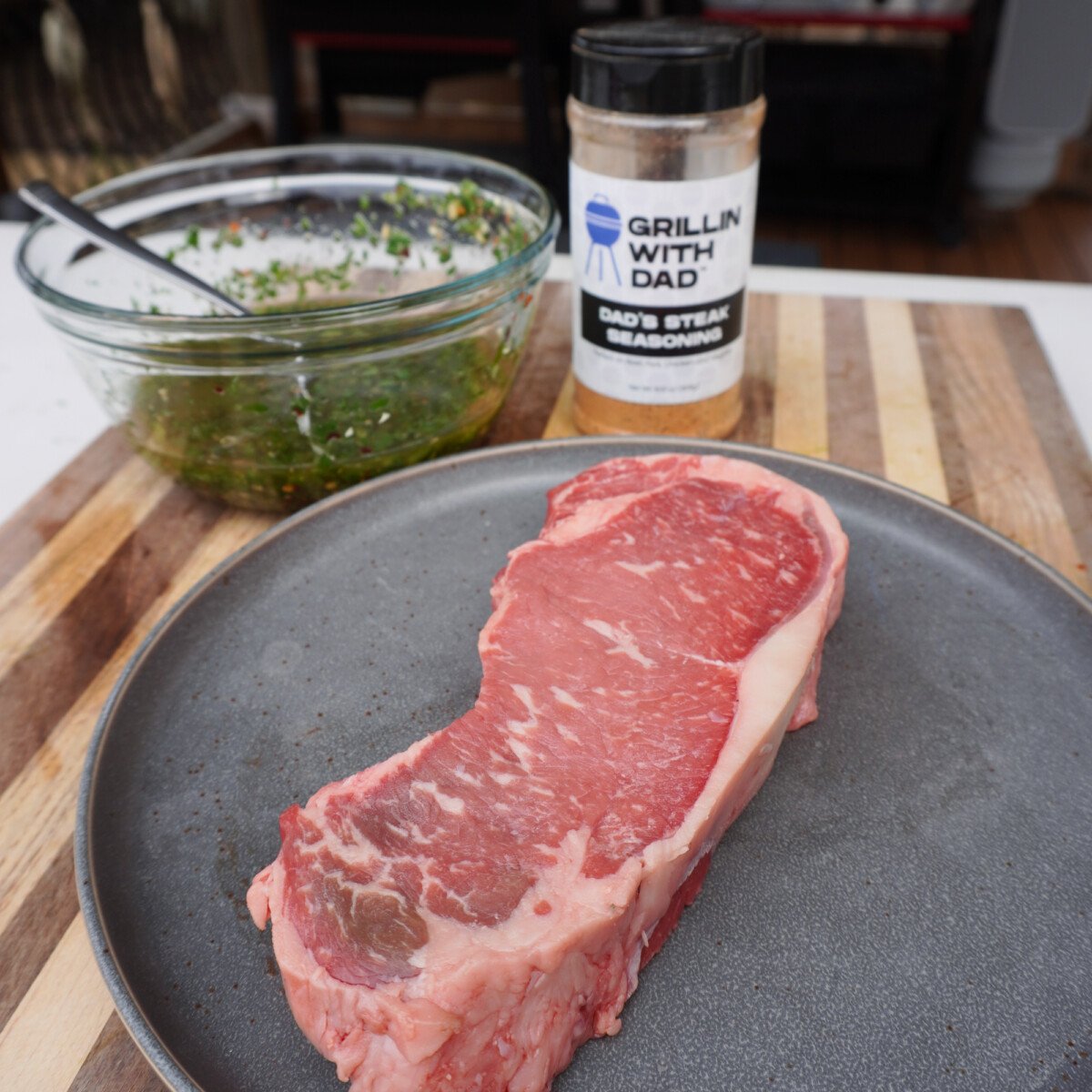 raw steak with seasoning and chimichurri sauce.