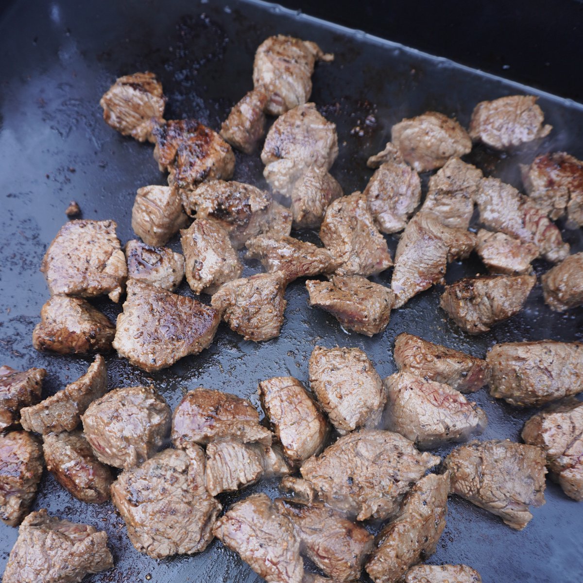 grilled garlic steak bites on a griddle.