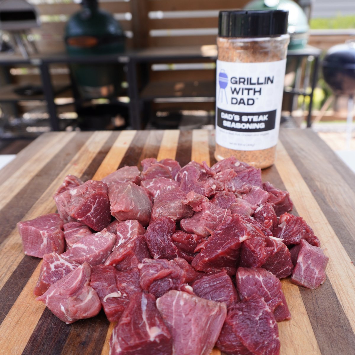 cut up beef trimmings on a wooden cutting board and a bottle of steak seasoning.