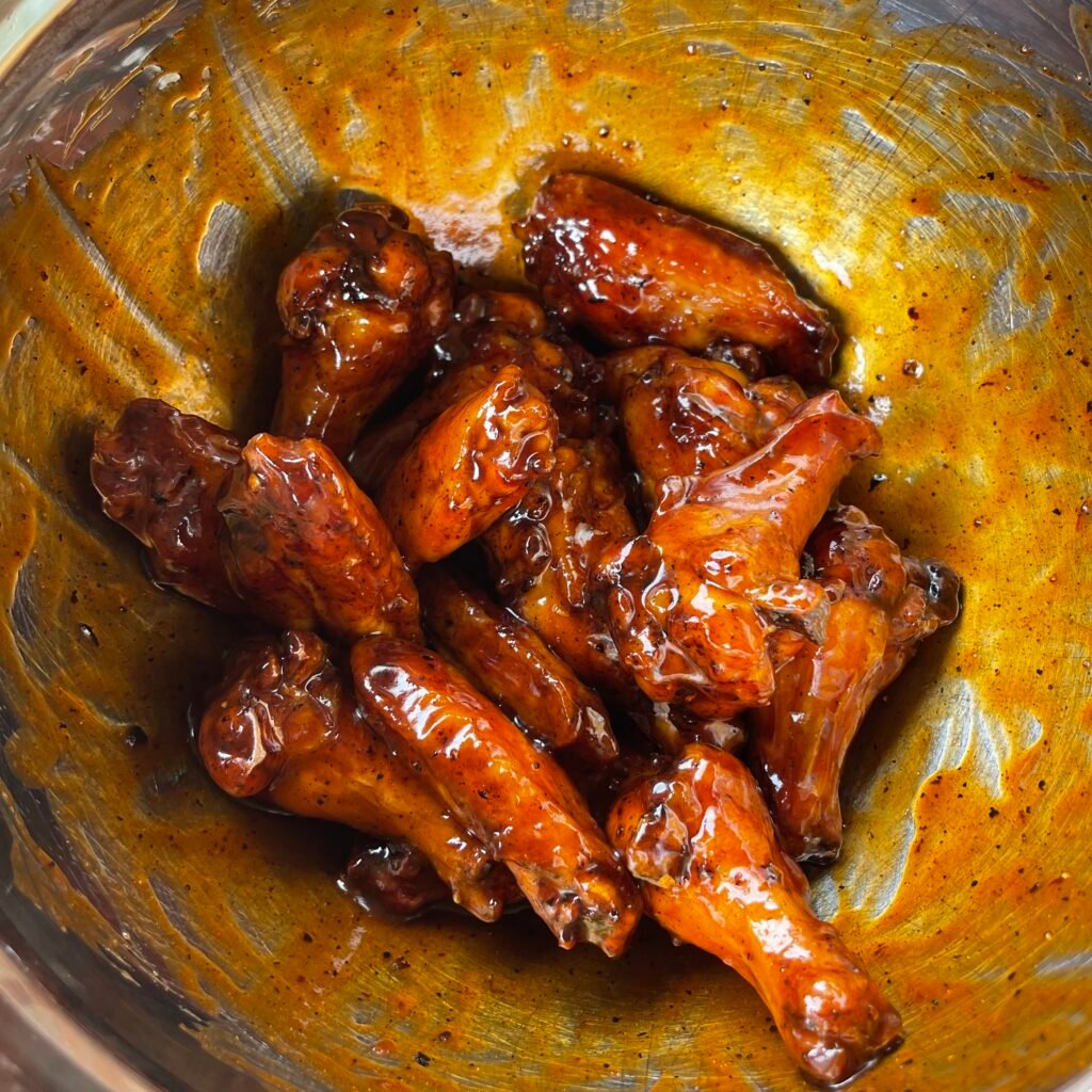 wings tossed in the sweet and spicy sauce in a bowl.