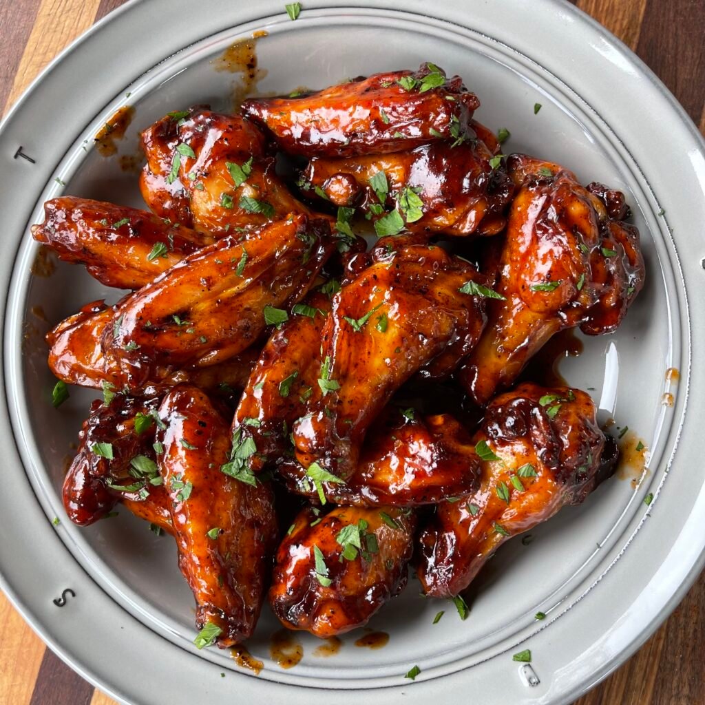 grilled sweet and spicy wings on a plate, topped with parsley. 