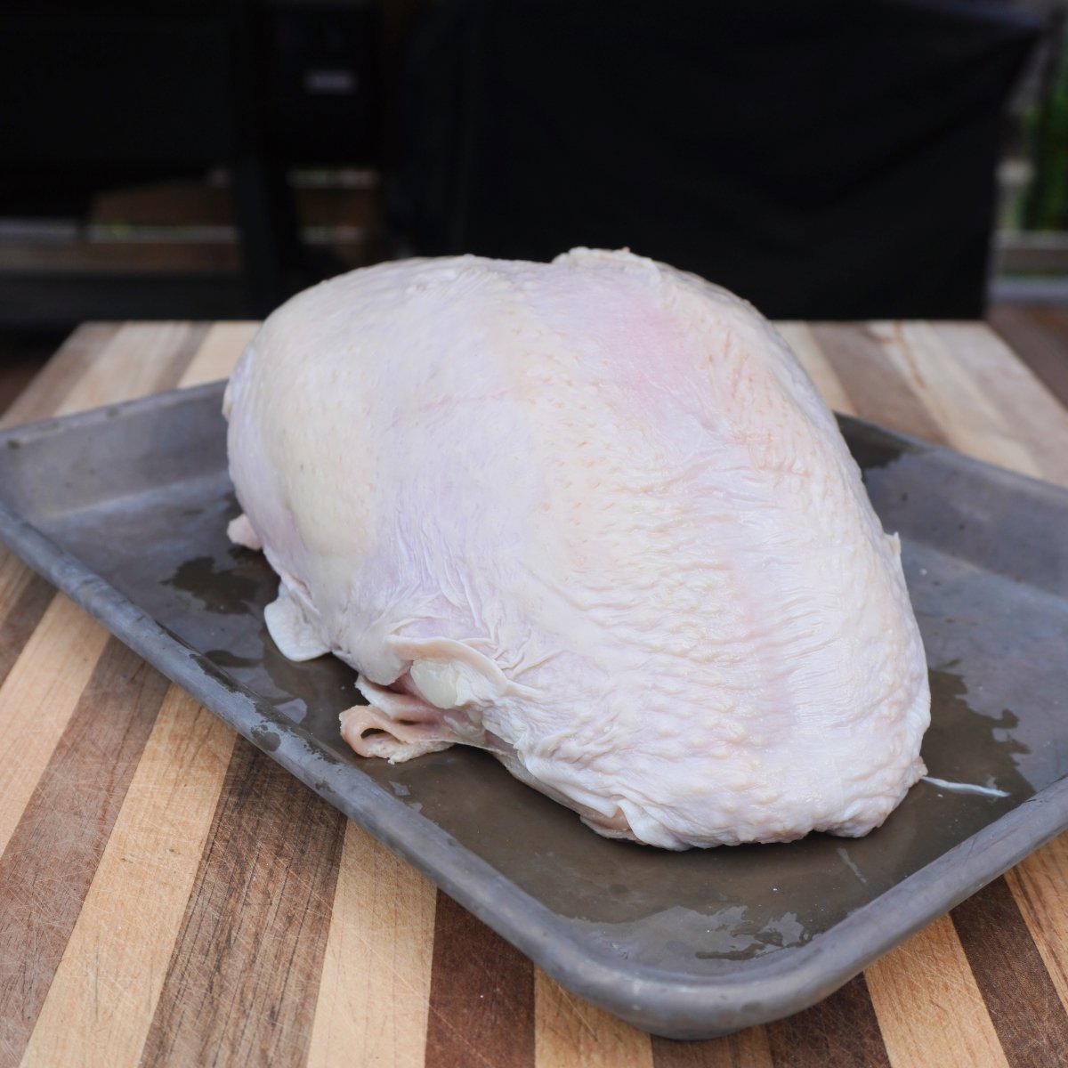 raw turkey breast on a tray on cutting board. 