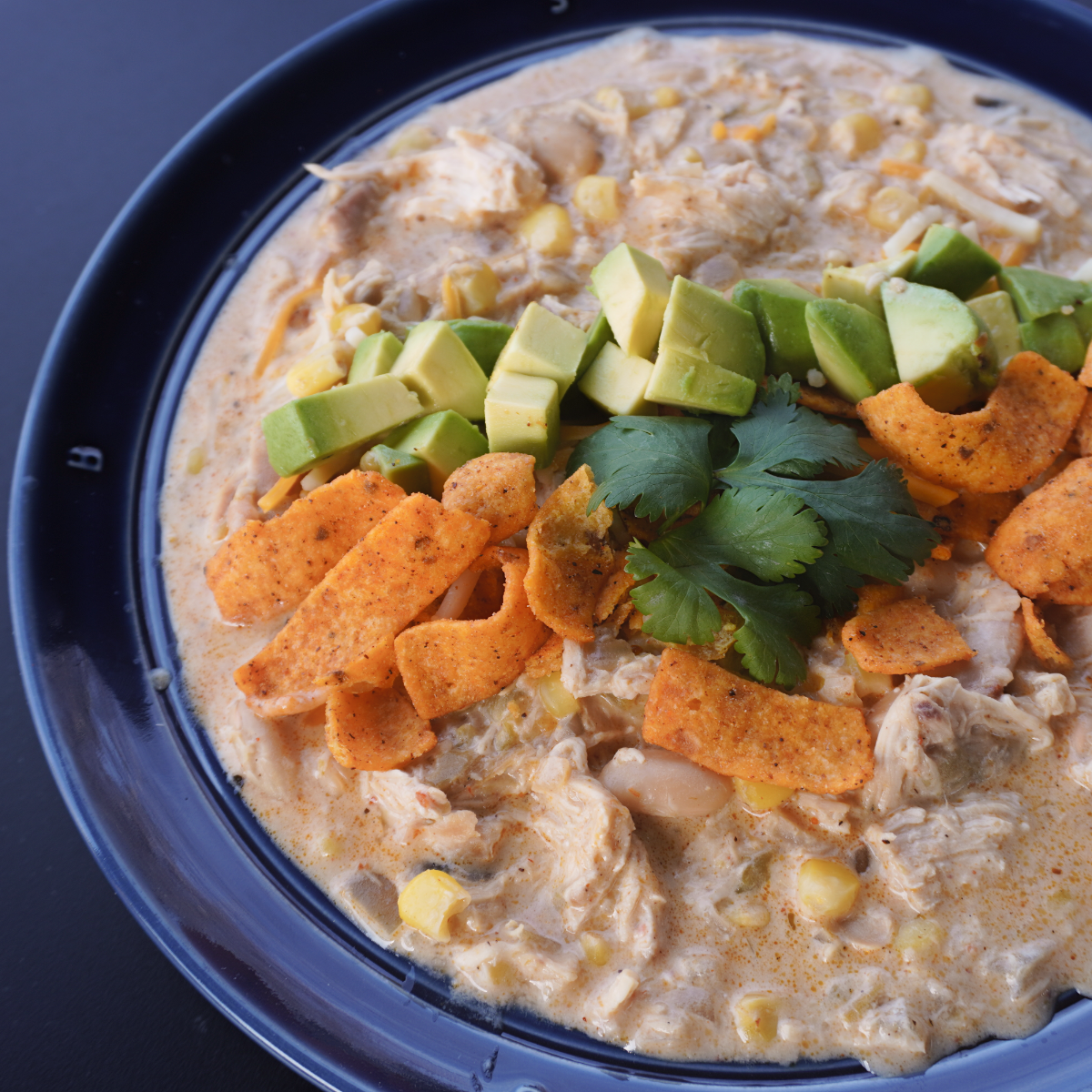 white chicken chili in a bowl with chips and avocado on top. 